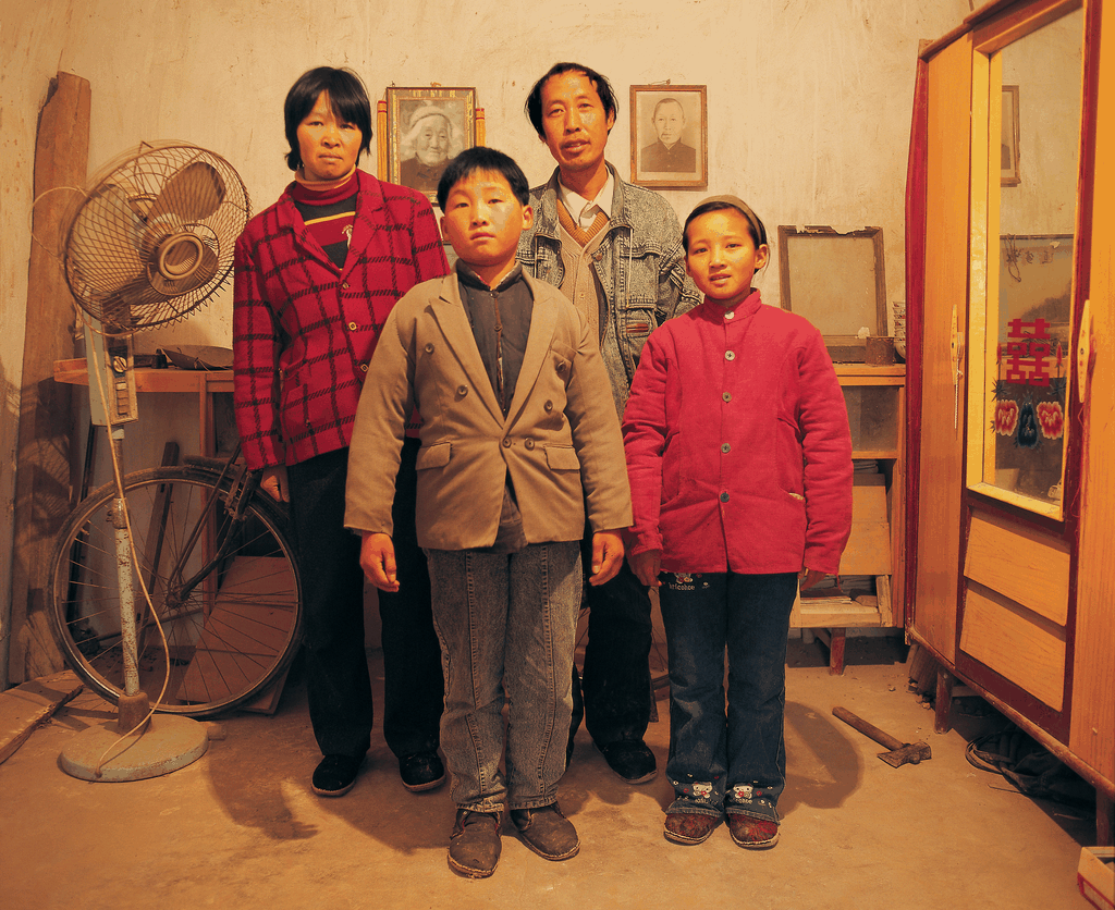 一张典型的90年代末中国农村家庭合影，一家四口在堂屋内严肃站立