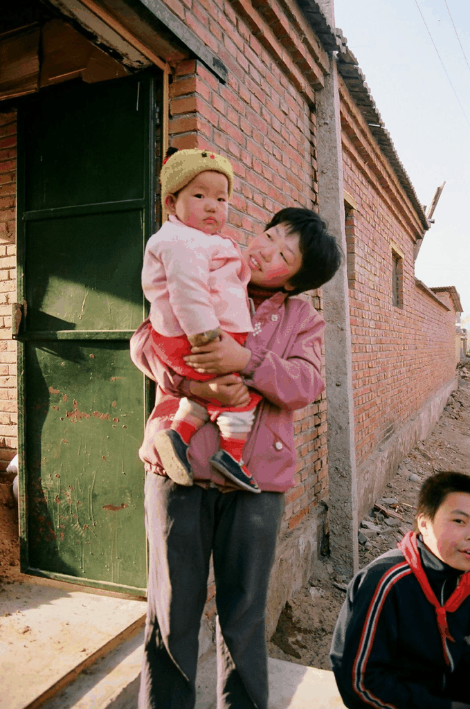 抱着孩子的年轻女子与戴红领巾的少年
