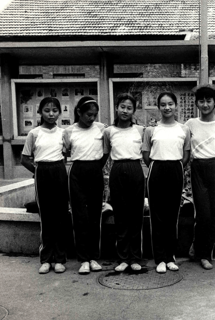 五个穿着统一运动服的女孩站在宣传栏前