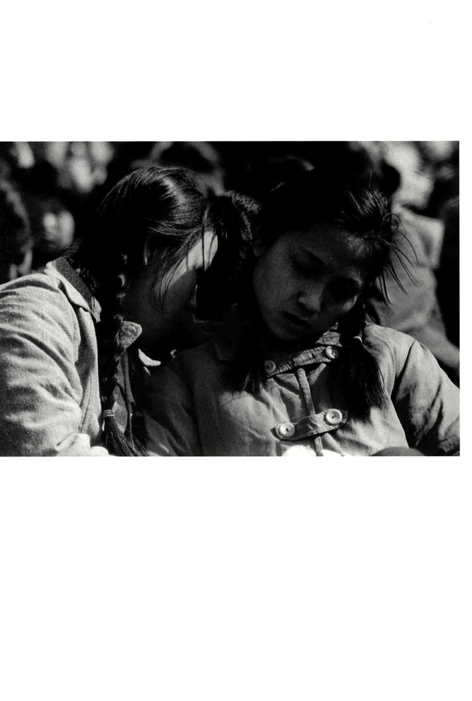 两个穿着朴素棉衣的女孩在人群中亲昵低语